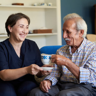 Professional helpful caregiver and a senior man during home visit