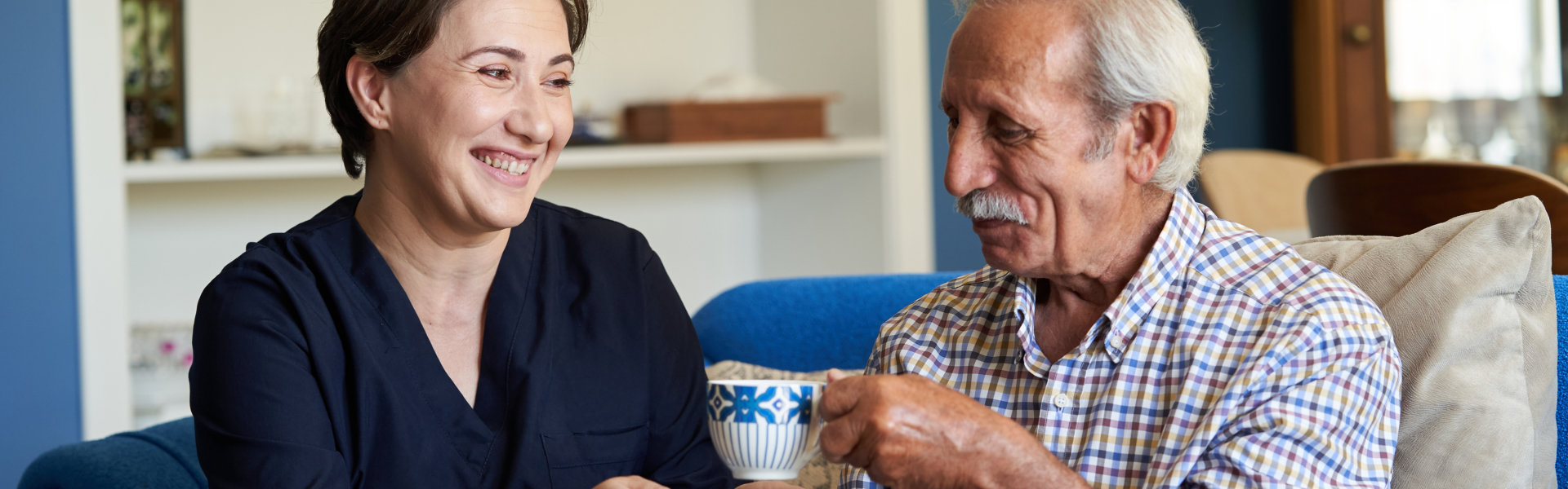 Professional helpful caregiver and a senior man during home visit